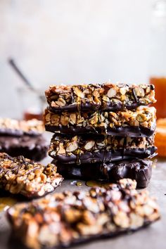 chocolate covered granola bars stacked on top of each other next to oranges and an orange juice