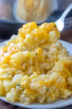 a spoonful of macaroni and cheese is being lifted from a white plate