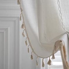 a white curtain with tassels hanging from it