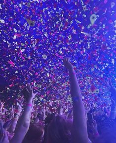 a large group of people at a concert with confetti falling from the ceiling