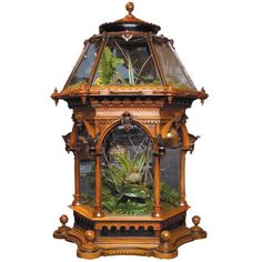 an ornate wooden clock with plants in the center and glass top on black back ground