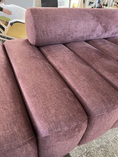 a purple couch sitting on top of a carpeted floor