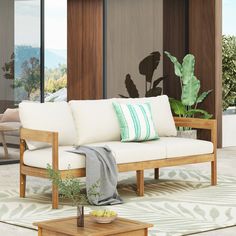 a white couch sitting on top of a living room floor next to a wooden table