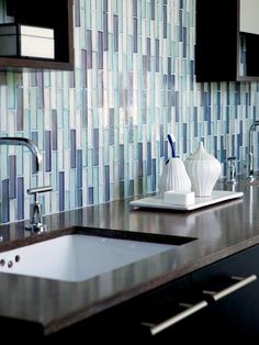 two white vases sitting on top of a counter next to a sink and faucet