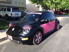 a pink and black car is parked on the side of the road in front of a house