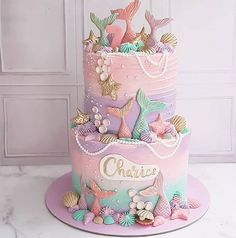 a three tiered cake decorated with mermaid decorations