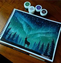 a notebook with some markers on it and an image of a deer in the woods