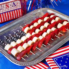 red, white and blue fruit skewers on a tray