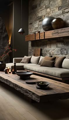 a living room filled with lots of furniture and stone wall behind the couches is a wooden coffee table