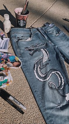 a pair of jeans with a snake painted on the side and other items scattered around