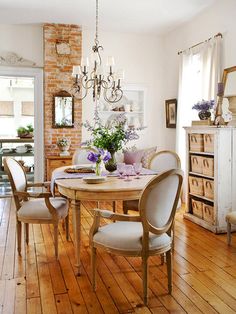 a dining room table with chairs and a chandelier hanging from it's ceiling