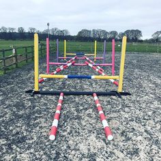 an obstacle course in the middle of a field with pink and yellow poles on it