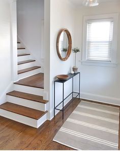 there is a mirror and some stairs in this house with wood floors on both sides