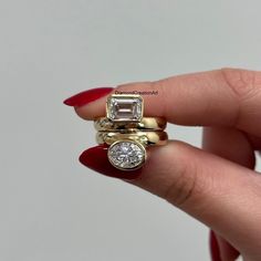 a woman's hand holding three rings with diamonds on them and one diamond in the middle