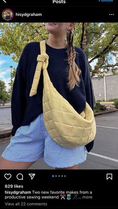 a woman wearing shorts and a sweater with a banana shaped bag attached to her waist