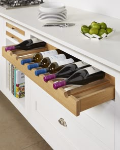 a kitchen with white cabinets and drawers filled with bottles of wine on the counter top