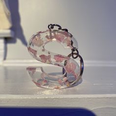 the letter s is made out of glass and has pink flowers on it's sides