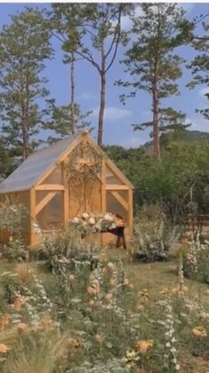 a small wooden building surrounded by trees and flowers