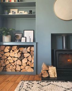 there is a fire place in the corner of this living room with wood stacked up