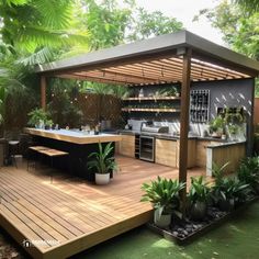 an outdoor kitchen with wooden decking and potted plants on the counter top, surrounded by greenery