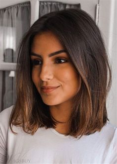 a woman with long hair is smiling at the camera while wearing a white t - shirt