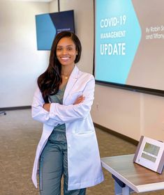 a woman standing in front of a projector screen with her arms crossed and smiling