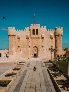 a large castle like building sitting on top of a lush green field next to palm trees