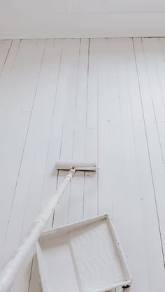 the floor is white and there is a paint roller on it next to an empty tray