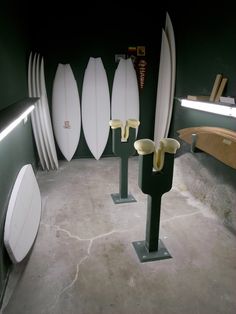 several surfboards are lined up against the wall in a room with green walls and concrete flooring