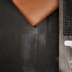 an overhead view of a desk with a keyboard, mouse and leather pillow on it