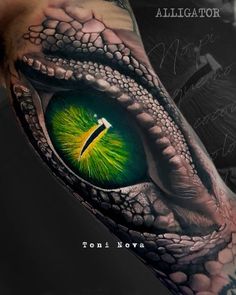 an eyeball tattoo on the arm that looks like a lizard's eye with green and yellow colors