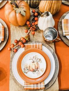 the table is set with plates and pumpkins