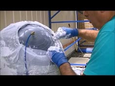 a man in blue shirt pouring water onto a large bag on top of a machine