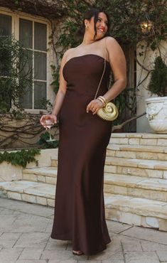 a woman in a brown dress is standing on some steps and posing for the camera