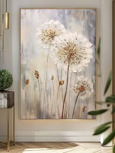 an abstract painting with white flowers on a beige background in a living room, next to a plant