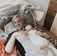 a man laying on top of a bed holding a baby