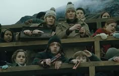 a group of people standing next to each other on top of a wooden bench in front of a mountain