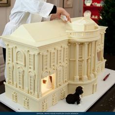 a woman in a chef's hat is decorating a white building with black poodles