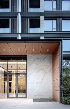 the entrance to an office building with glass doors and wooden paneling on the outside