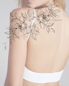 the back of a woman's shoulder with flowers tattooed on her arm and chest