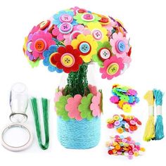 a vase filled with lots of colorful buttons and flowers next to other crafting supplies