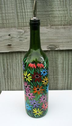 a green glass bottle with colorful flowers painted on it