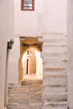 an alley way with steps leading up to a window in the wall and stone flooring