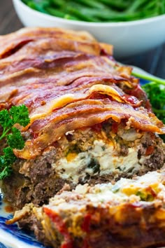 meatloaf stuffed with cheese and vegetables on a blue plate next to green beans