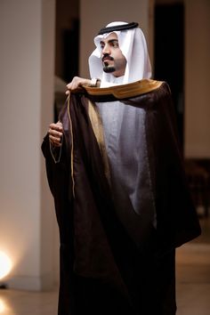 a man dressed in an arabian outfit holding a piece of cloth with his hand on it