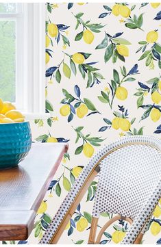 a bowl of lemons sitting on top of a table next to a wallpaper