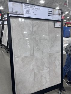 a person pushing a shopping cart in a store with marble tiles on the walls and floor