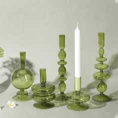 a group of green glass vases and candles