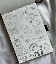 an open notebook with drawings on it sitting on top of a white sheet covered in black ink