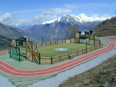 an outdoor tennis court on top of a mountain with mountains in the backgroud